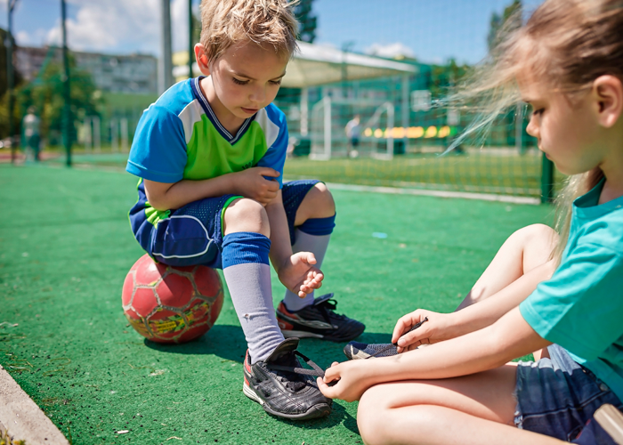 Amico aiuta il figlio a prepararsi per la sua prima lezione di calcio ad Aprilia